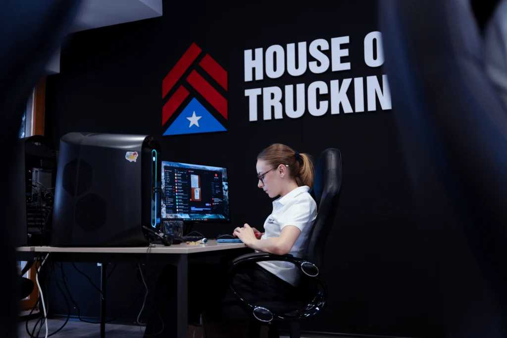 House of Trucking employee working at a computer station with company logo on the wall
