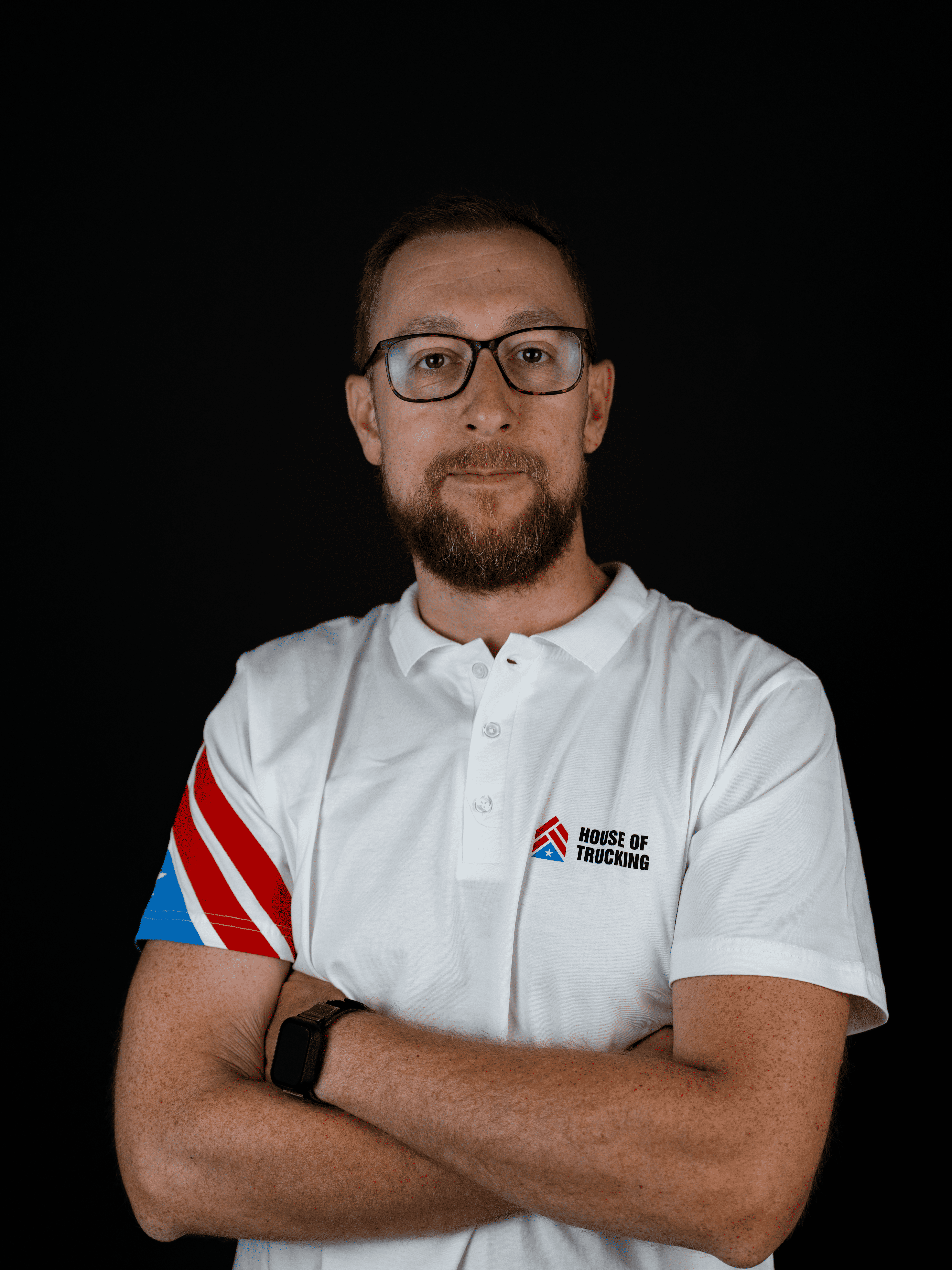 Portrait of Dane, Co-Founder and Chief of People & Culture at House of Trucking, wearing company uniform with folded arms.