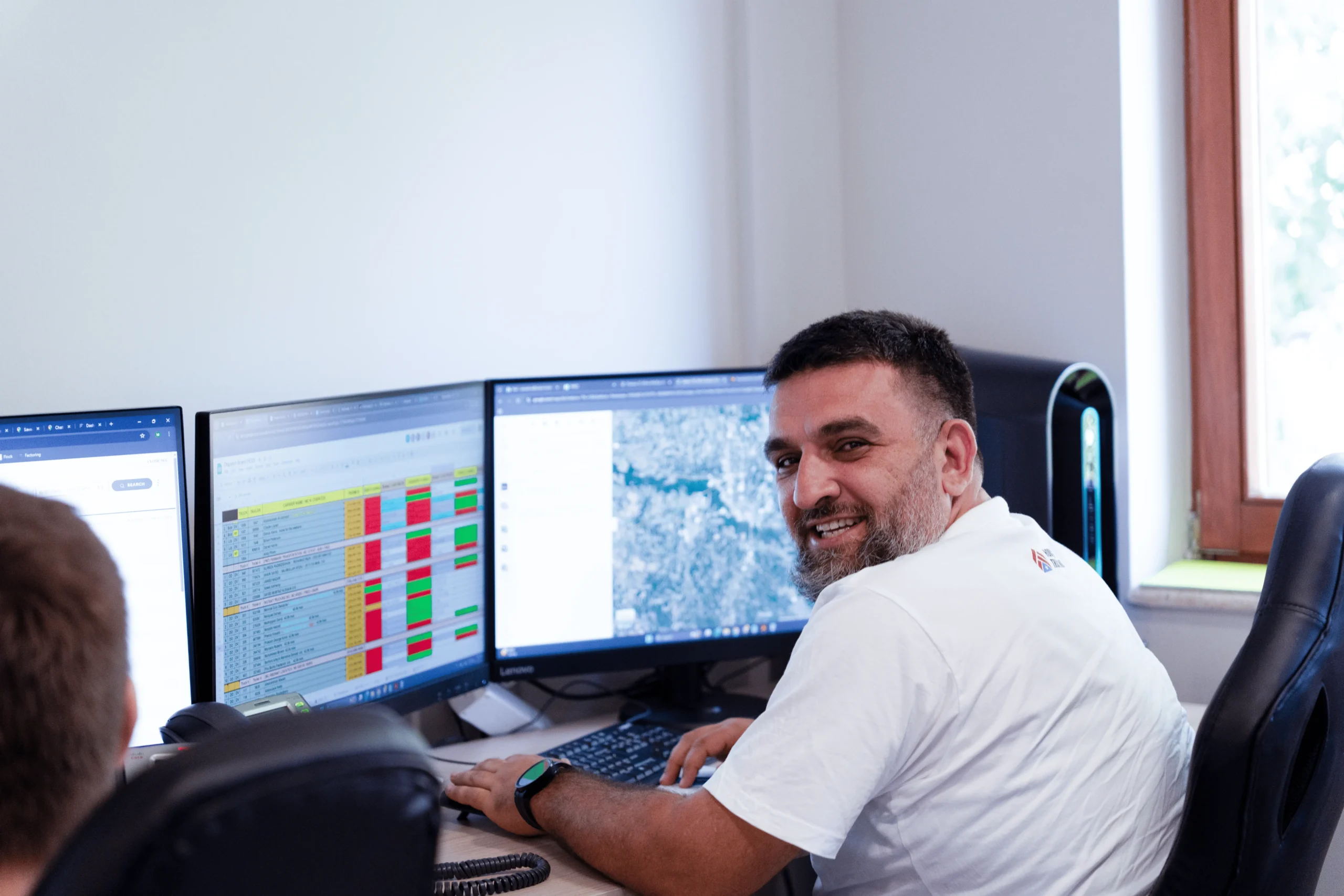 Dispatcher working at desk with multiple monitors tracking loads and routes