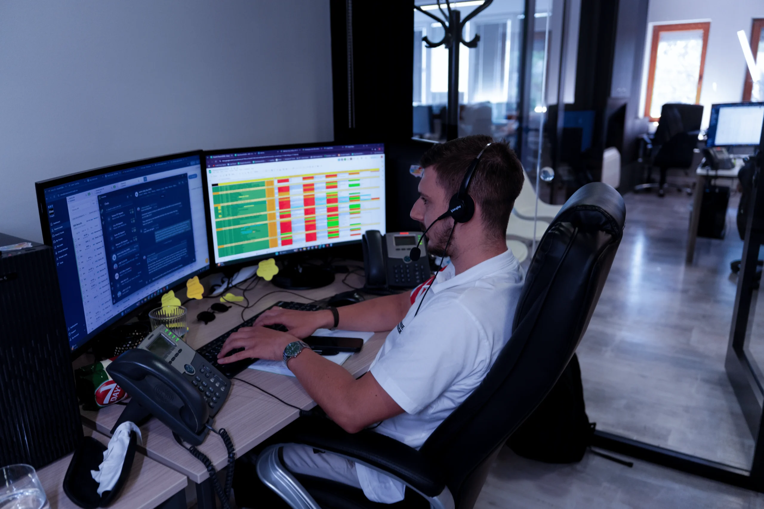 Dispatcher monitoring real-time trucking operations with dual screens