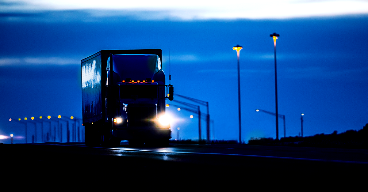Semi-truck driving at night on a highway with bright lights, symbolizing truck driver alertness