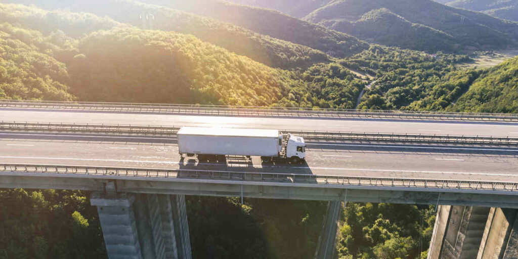Truck driving on a highway bridge symbolizing FMCSA registration and compliance (MCS-150 guide)