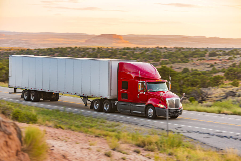 Red semi-truck hauling a dry van trailer on the highway – freight transport example